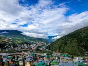  A panoramic view of Bhutan's townscape from a mountain summit, showcasing lush greenery and traditional architecture.