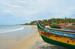 Colorful boats lined on a sandy beach, with the ocean waves gently lapping nearby, showcasing a coastal offbeat destination.