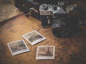 A vintage Polaroid camera surrounded by travel photos, a map, and a travel guide, evoking a sense of adventure.