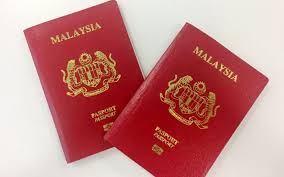 Two Malaysian passports displayed on a white background, showcasing their distinct design and colors.