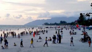 A bustling beach scene filled with people enjoying the sun, surrounded by colorful umbrellas dotting the sandy shore.