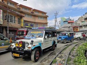  A line of jeeps driving through a bustling city street, surrounded by tall buildings and urban scenery.