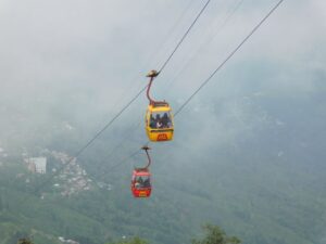 Two cable cars glide above a majestic mountain landscape, showcasing the beauty of nature and engineering.