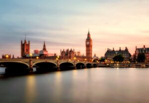 Big Ben clock tower and the Houses of Parliament silhouetted against a vibrant sunset sky.