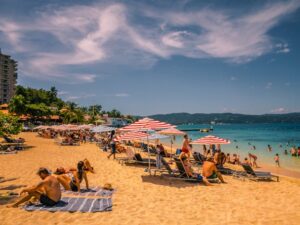  People enjoy leisure time on a sunny beach at a resort in the Dominican Republic, surrounded by palm trees and clear waters. 