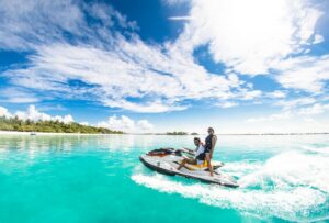 Two individuals enjoy a thrilling jet ski ride in the ocean, perfect for a Maldives honeymoon adventure.