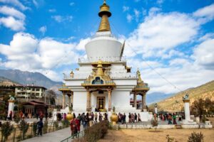 People walking around a tranquil Buddhist temple set against a stunning mountain backdrop.