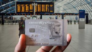 A traveler displays a credit card in front of an airport terminal, ready for check-in or purchases.